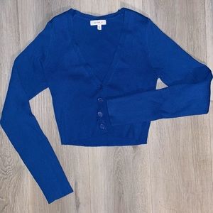 A tight dark blue cropped cardigan, is a size M , & branding from “BETTER BE”
